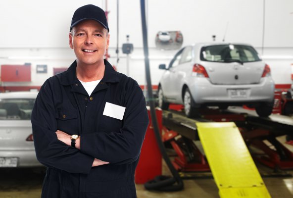 best extended car warranty services providers happy mechanic in uniform smiling towed car on platform in the background 